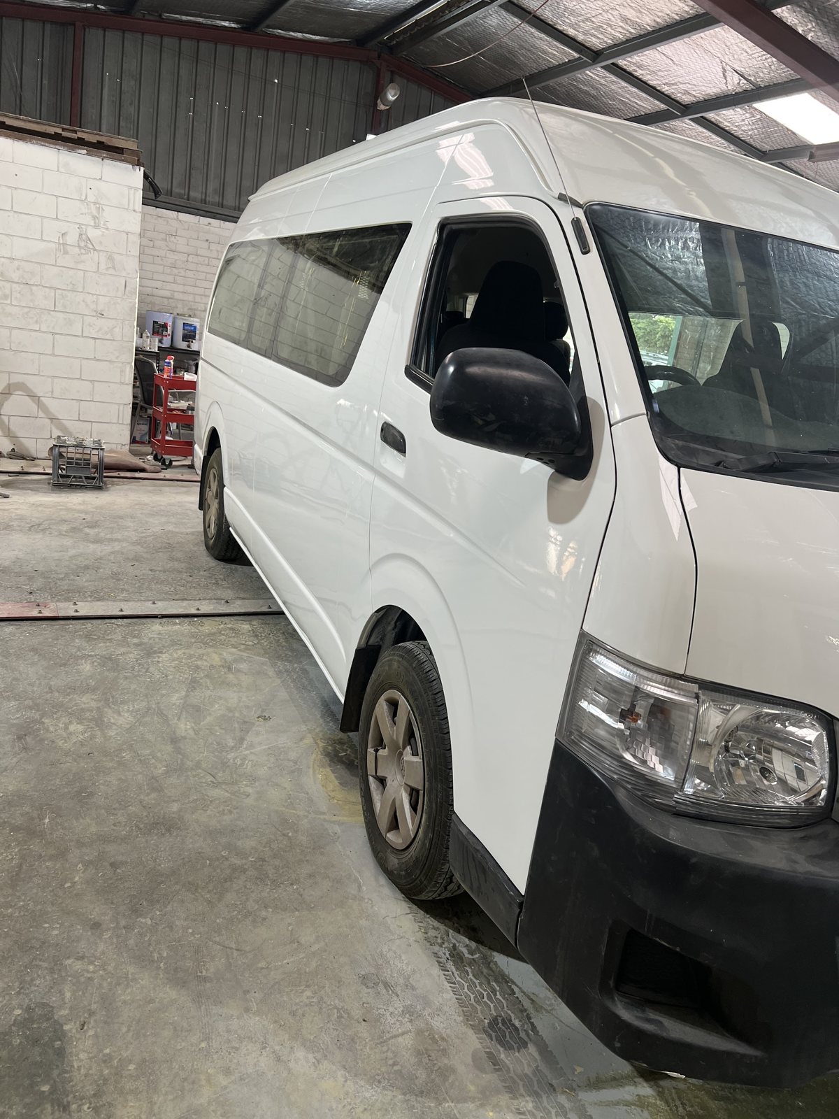 White Toyota Hiace van parked inside the workshop under the steel roof