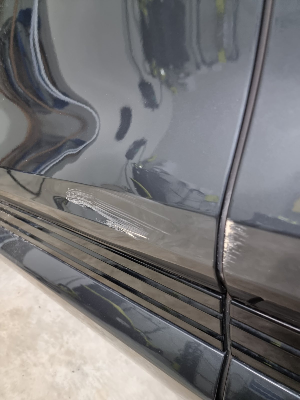 Close-up of scratches along the sill and lower door of a black car